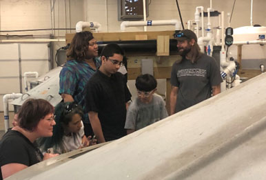 USM’s Andy Gima, systems specialist at the Thad Cochran Marine Aquaculture Center in Ocean Springs, explains to teachers the importance of tank design in aquaculture. (Photo by Tara Skelton)