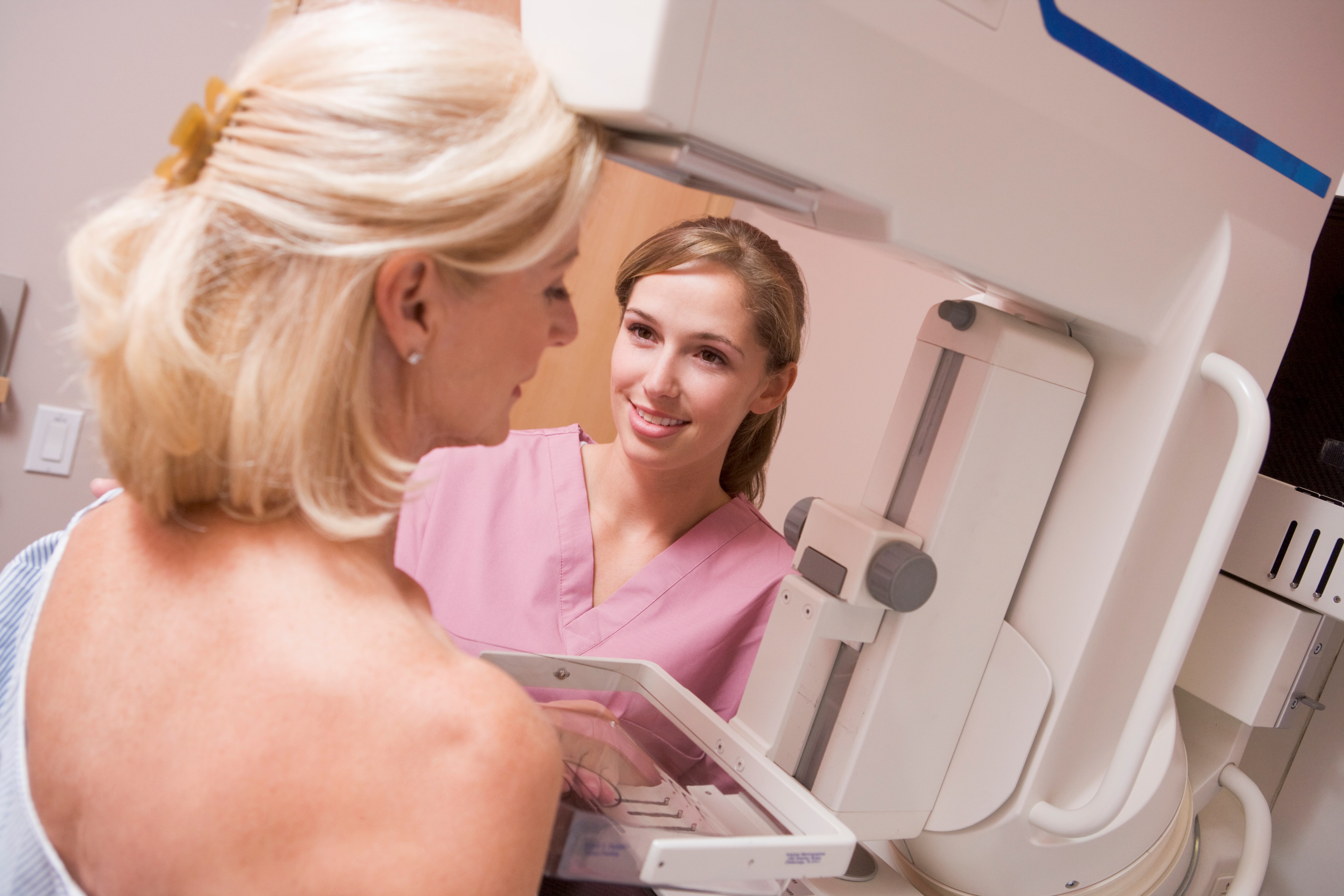 Woman receives a mammogram from a female nurse.