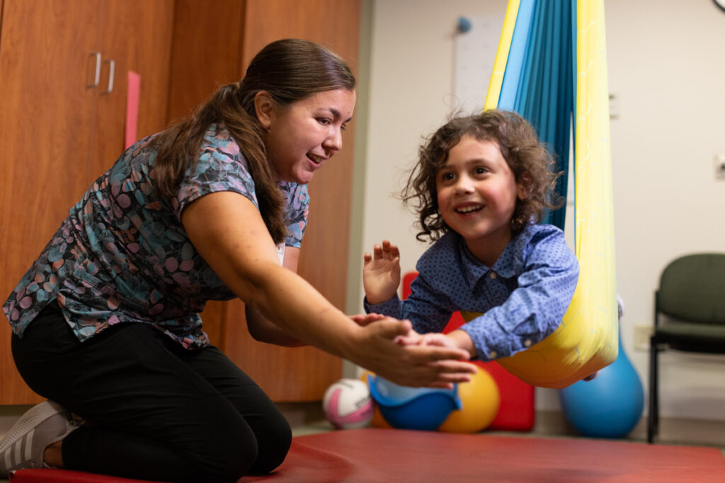 Child is in a swing during occupational therapy session.