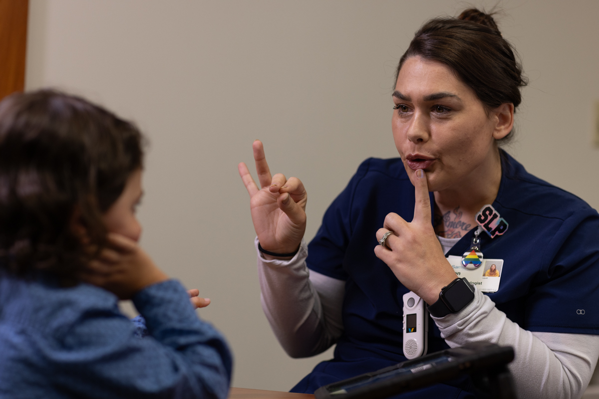Therapy session shows the speech pathologist signing to patient.